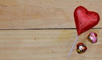 Chocolate heart wrapped in red  on wood. valentine concept. Space for text. photo