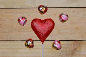 Chocolate heart wrapped in red  on wood. valentine concept. Space for text. photo