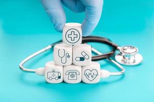 concepto de seguro de salud. símbolos médicos en bloques de forma de cubo y mano sosteniendo un bloque con icono médico de atención médica foto