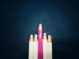 White and pink pencils are placed on a black leather surface with black edges in vintage style, giving the idea of business growth. and leadership photo