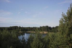 Summer landscape with a beautiful lake with fir trees and forested mountains against a cloudy sky photo