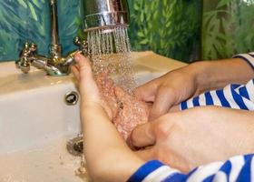 Close up of caucasian man and child washes his hands in the bathroom. COVID - 19 prevention photo