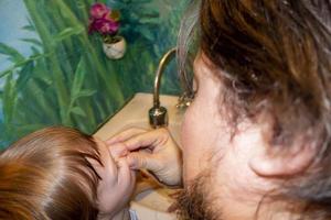 a man and a boy in vests wash their faces photo