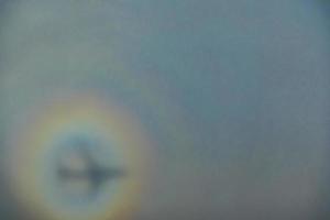 blurry shadow of the airplane on the cloud with the rainbow circle. traveling concept photo