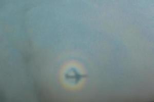 blurry shadow of the airplane on the cloud with the rainbow circle. traveling concept photo