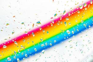 A rainbow behind a glass windows with water drops, Point of view, from behind the glass with drops. photo