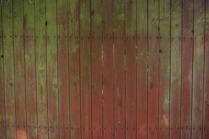 Close up of scratched red and green wooden texture of a fence. Red and green wooden planks photo