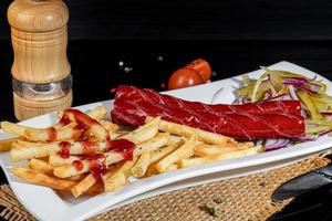 Smoked sausages with french fries and pickles. Snack for beer. Dark background. photo