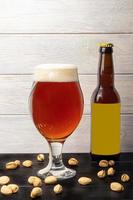 Glasses with different types of craft beer on a wooden bar. In glasses and bottles. Nuts and crackers on the table. On a dark background. photo