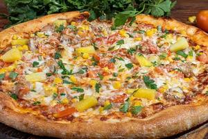 Pizza with bacon and cheese, herbs and cherry tomatoes. With mozzarella, shrimps and octopuses, mussels and other products on a wooden background. photo