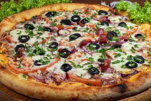 Pizza with bacon and cheese, herbs and cherry tomatoes. With mozzarella, shrimps and octopuses, mussels and other products on a wooden background. photo