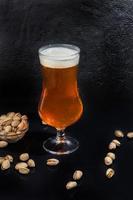 Glasses with different types of craft beer on a wooden bar. In glasses and bottles. Nuts and crackers on the table. On a dark background. photo