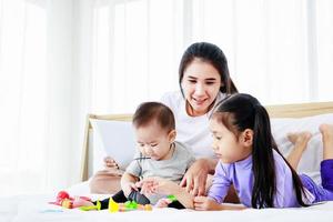 Busy mother with two daughters multitasking with laptop, Super mom concept photo