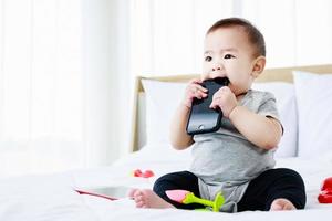 Joyful baby girl paying with toy on the bed photo