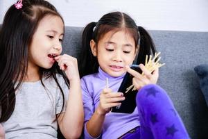 Two happy cute little girls playing game on smartphone together at home photo