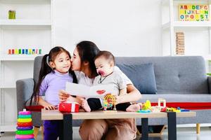 cute daughter sends love mom gift to mother and kiss while play with baby, Mother day concept photo