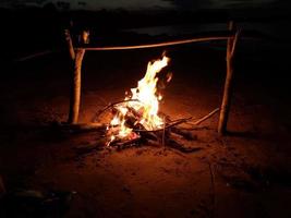 The bonfire burns in the evening on the shore of the lake photo