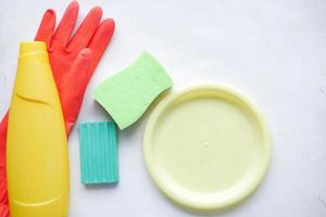 esponja, guantes de goma y plato de colores sobre rosa foto