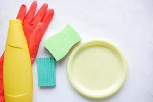 sponge , rubber gloves and colorful plate on pink photo