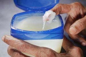 senior woman using petroleum jelly onto skin photo