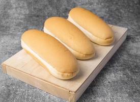 Close up long bread for hot dogs on a wood plate. photo