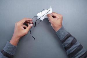 cleaning eyeglass with tissue close up photo