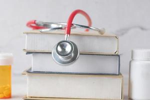 stethoscope on a stack of books on table photo