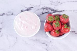 Yogurt and strawberry in a bowl on white photo