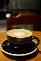 una taza de café tardío con un diseño en forma de flor en la parte superior del café foto