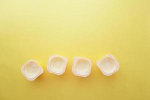 fresh yogurt in a plastic container and spoon on table photo