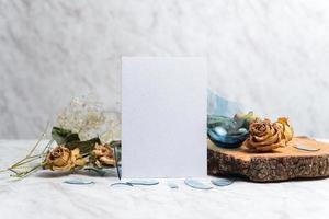 Blank card and wilted flowers on marble background