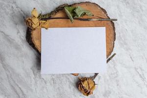 Blank card and wilted flowers on marble background
