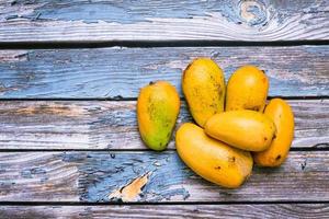 Group of ripe mangoes in dark environment on wooden table. photo