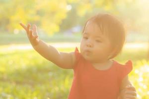 cara de retrato de linda niña asiática y felicidad y diversión infantil en el parque en verano, sonrisa y felicidad de niño asiático y relajación en el jardín, concepto de infancia de estilo de vida. foto