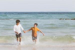 Homosexual portrait young asian couple running with cheerful together on beach in summer, asia gay going tourism for leisure and relax with happiness in vacation at sea, LGBT legal concept. photo