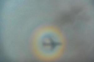 blurry shadow of the airplane on the cloud with the rainbow circle. traveling concept photo