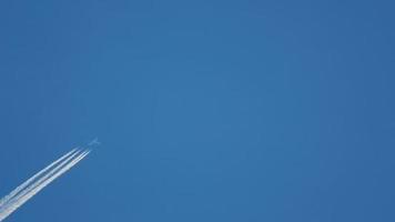 Contrails in the blue sky. Airplane flying high. Slow motion video