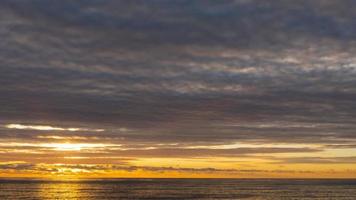 vista panoramica ravvicinata del sole che tramonta oltre l'orizzonte sul mare. lasso di tempo