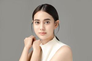 Beautiful young Asian woman model with perfect clean fresh skin on grey background. Face care, Facial treatment, Cosmetology, Plastic Surgery, Lovely girl portrait in studio. photo
