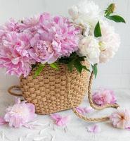 bolso de mimbre con flores de peonía foto
