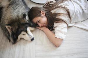 dueña de una mascota abrazándose con un cachorro de perro. feliz mujer humana y lindo perro divertido tirados en el suelo juntos foto