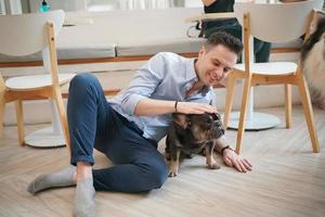Man and with his pet dog playing on the floor. Happy dog, happy guy with dog. photo