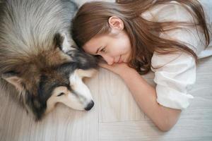 dueña de una mascota abrazándose con un cachorro de perro. feliz mujer humana y lindo perro divertido tirados en el suelo juntos foto