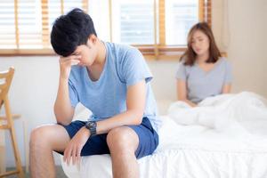 Asian young couple having problem of man worried impotent and unhappy at bedroom, trouble divorce of family with frustrated, husband having depression, conflict of love concept. photo