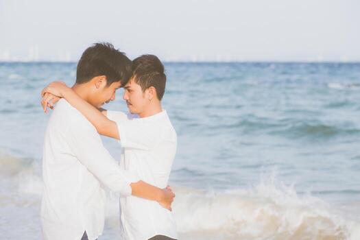 Homosexual portrait young asian couple standing hug together on beach in summer, asia gay going tourism for leisure and relax with romantic and happy in vacation at sea, LGBT legal concept. photo