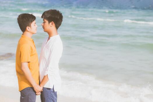 Homosexual portrait young asian couple standing together on beach in summer, asia gay holding hands going sea for leisure and relax with romantic and happy in vacation at sea, LGBT with legal concept. photo