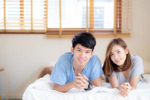 Beautiful portrait young asian couple relax and satisfied together in bedroom at home, family lying on bed confident with cheerful and happy with relationship, man and woman dating. photo