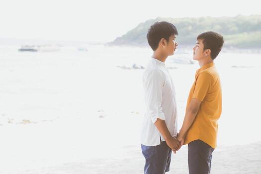 Homosexual portrait young asian couple standing together on beach in summer, asia gay holding hands going sea for leisure and relax with romantic and happy in vacation at sea, LGBT with legal concept. photo