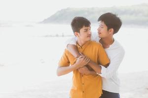 Homosexual portrait young asian couple standing hug together on beach in summer, asia gay going tourism for leisure and relax with romantic and happiness in vacation at sea, LGBT concept. photo