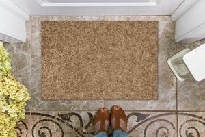 Blank doormat before the door in the hall. Mat on ceramic floor, flowers and shoes. Welcome home, product Mockup photo